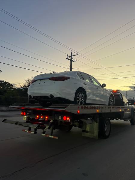 Grúa de plataforma cargando un carro al atardecer en West Palm Beach.